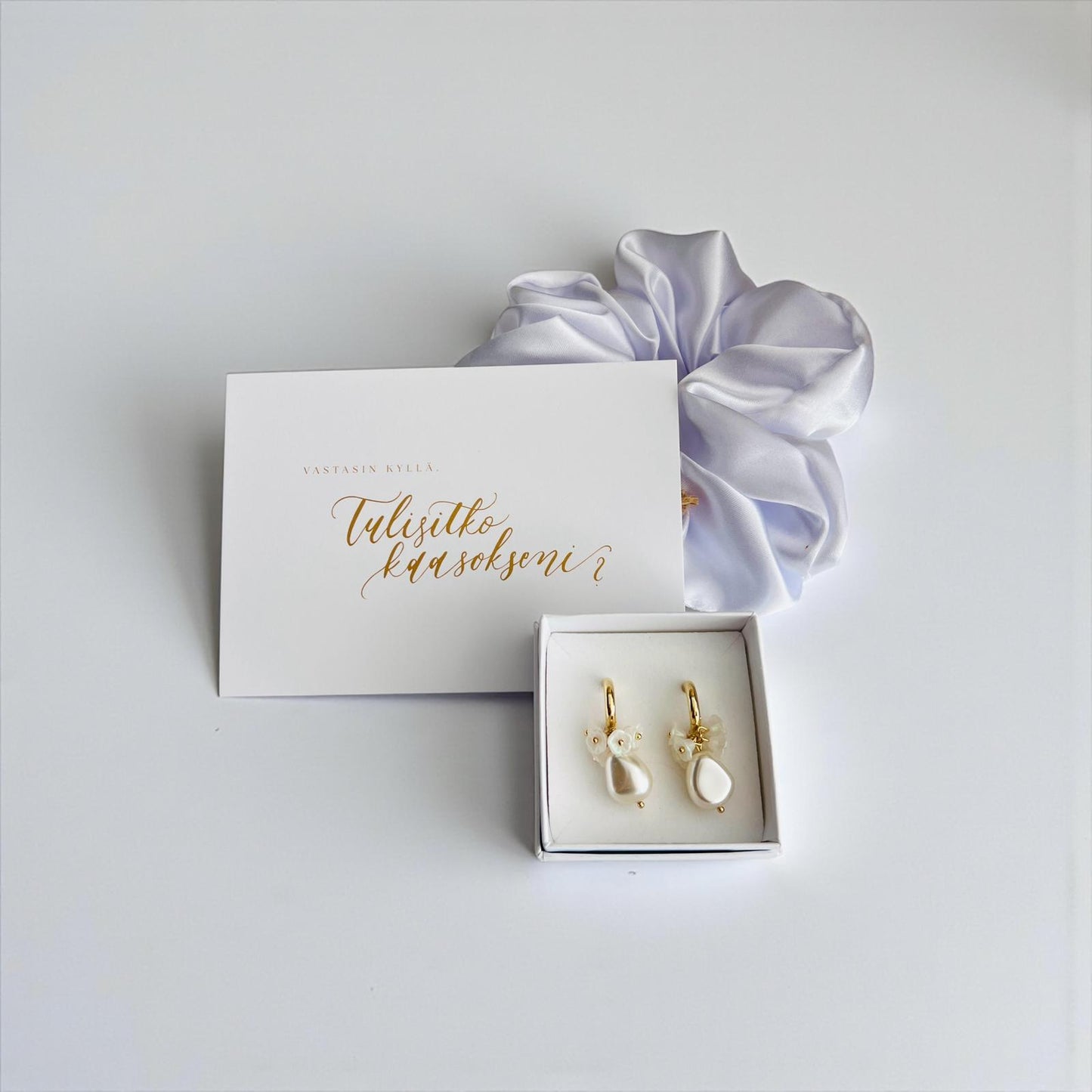 Tulisitko kaasokseni -kortti, valkoinen hiusdonitsi ja valkoiset korvakorut.