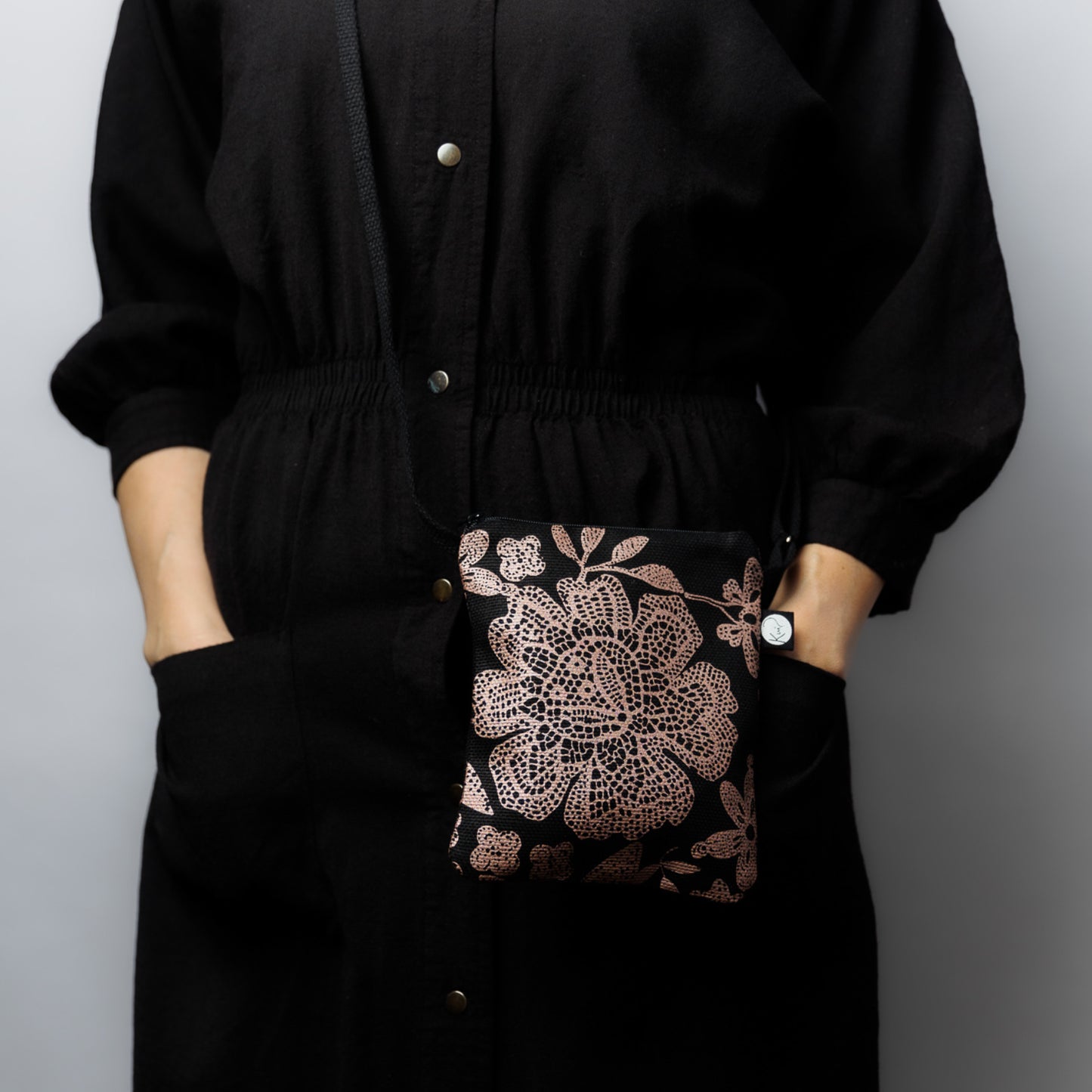 Mallin päällä Kui designin Hulda-pikkulaukku. Pohjaväri musta, kuparin värisiä kukkia.