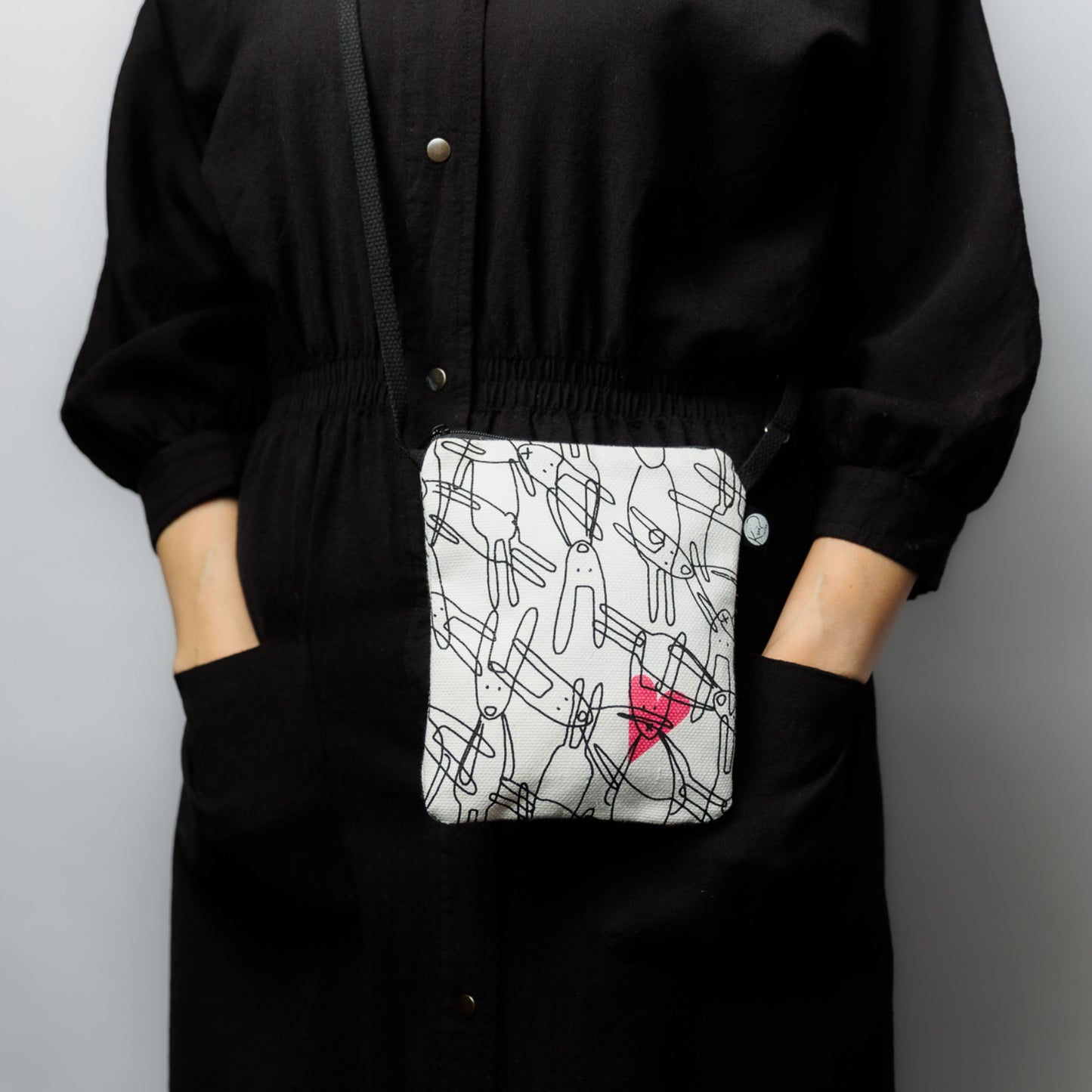 Mallin päällä Kui designin Pupuset-pikkulaukku. Pohjaväri valkoinen, musta pupu-grafiikka ja pinkki sydän.