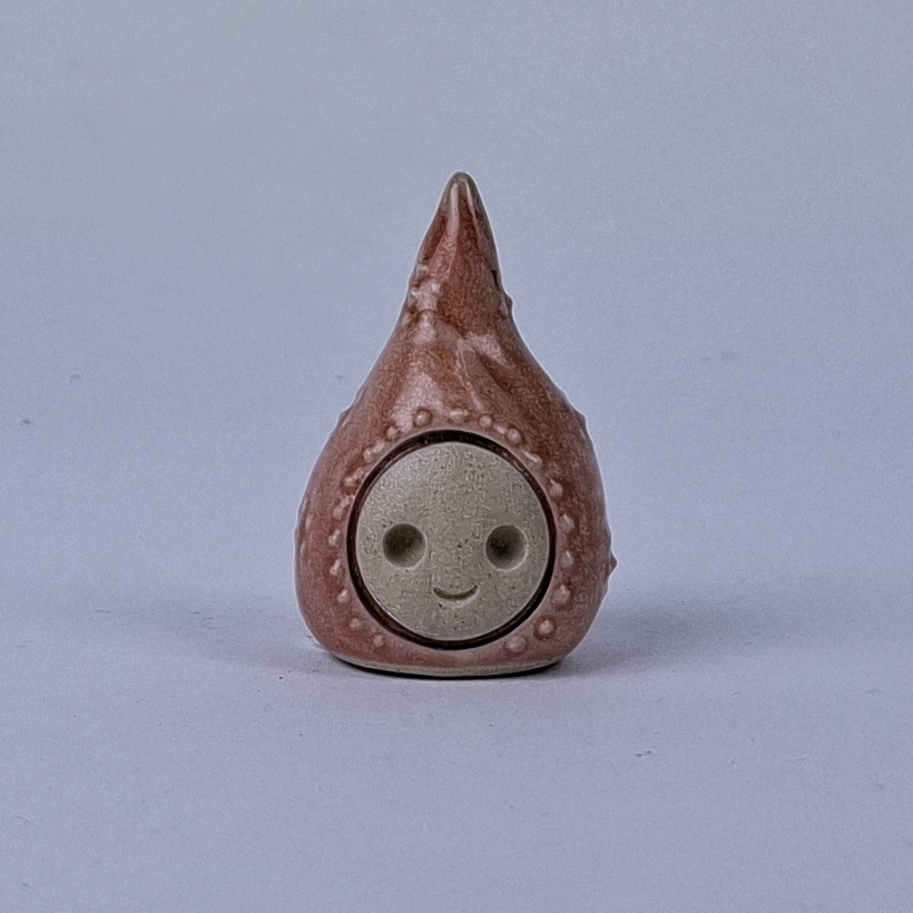 Kuparinen  keraaminen figuuri jonka pää kapenee ylöspäin
