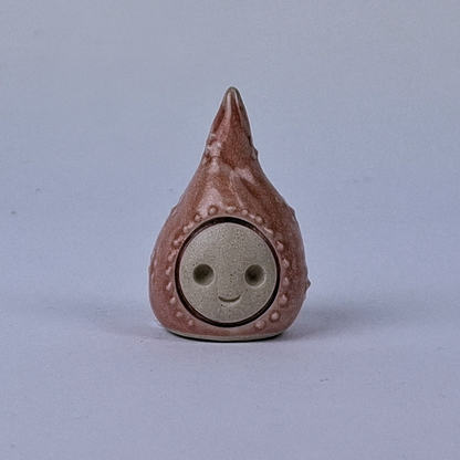 Kuparinen  keraaminen figuuri jonka pää kapenee ylöspäin