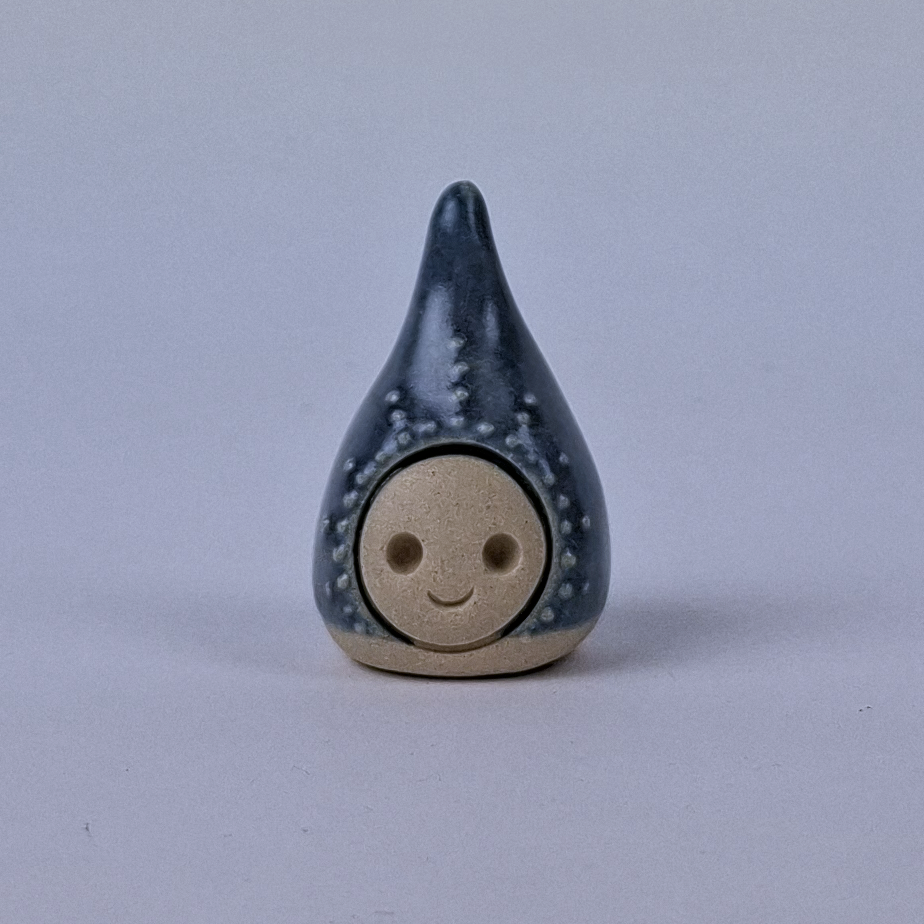 Tummansininen  keraaminen figuuri jonka pää kapenee ylöspäin