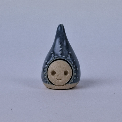 Tummansininen  keraaminen figuuri jonka pää kapenee ylöspäin