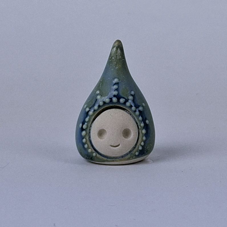 sinisen vihreä  keraaminen figuuri jonka pää kapenee ylöspäin