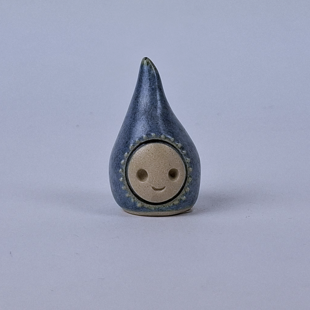 Sininen  keraaminen figuuri jonka pää kapenee ylöspäin