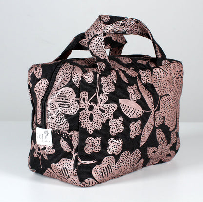 Kui designin Hulda-toilettilaukku. Musta pohjaväri, jossa kuparin värinen kukka kuosi.