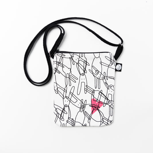 Kui designin Pupuset-pikkulaukku. Pohjaväri valkoinen, musta pupu-grafiikka ja pinkki sydän.