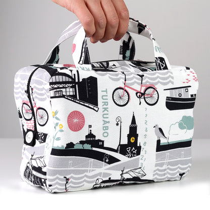 Kui designin Tälpal ja toispual-toilettilaukku. Valkoinen pohjaväri, jossa roosan värinen Turku-aiheinen kuosi.